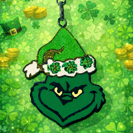 Green Grinch car freshie with shamrock decorations on a St. Patrick's Day themed background.