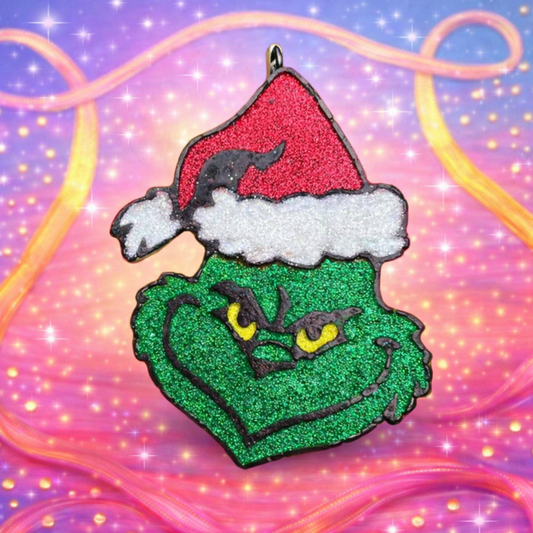 Glittery Grinch freshie with a Santa hat on a colorful, swirling background.