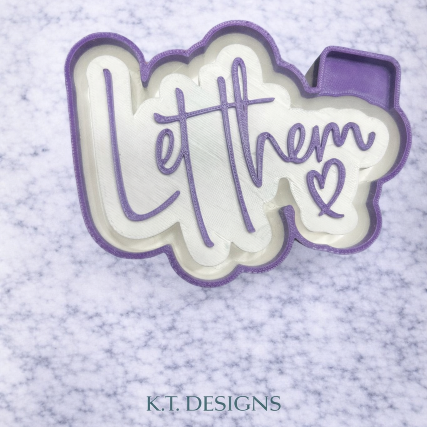 Decorative text 'Let them' with a heart on a textured light purple background, branded 'K.T. DESIGNS'.